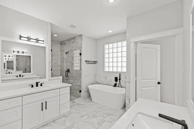 a bathroom with a double vanity sink large mirror and a bathtub
