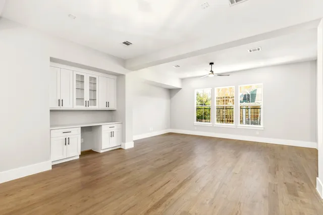 a view of an empty room with a window and wooden floor
