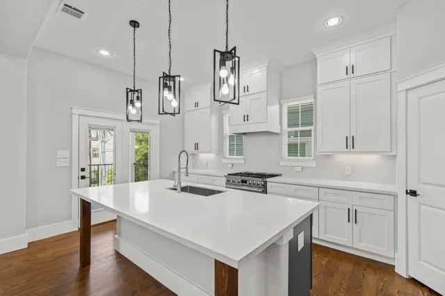 a kitchen with stainless steel appliances a stove a sink a center island and wooden floor