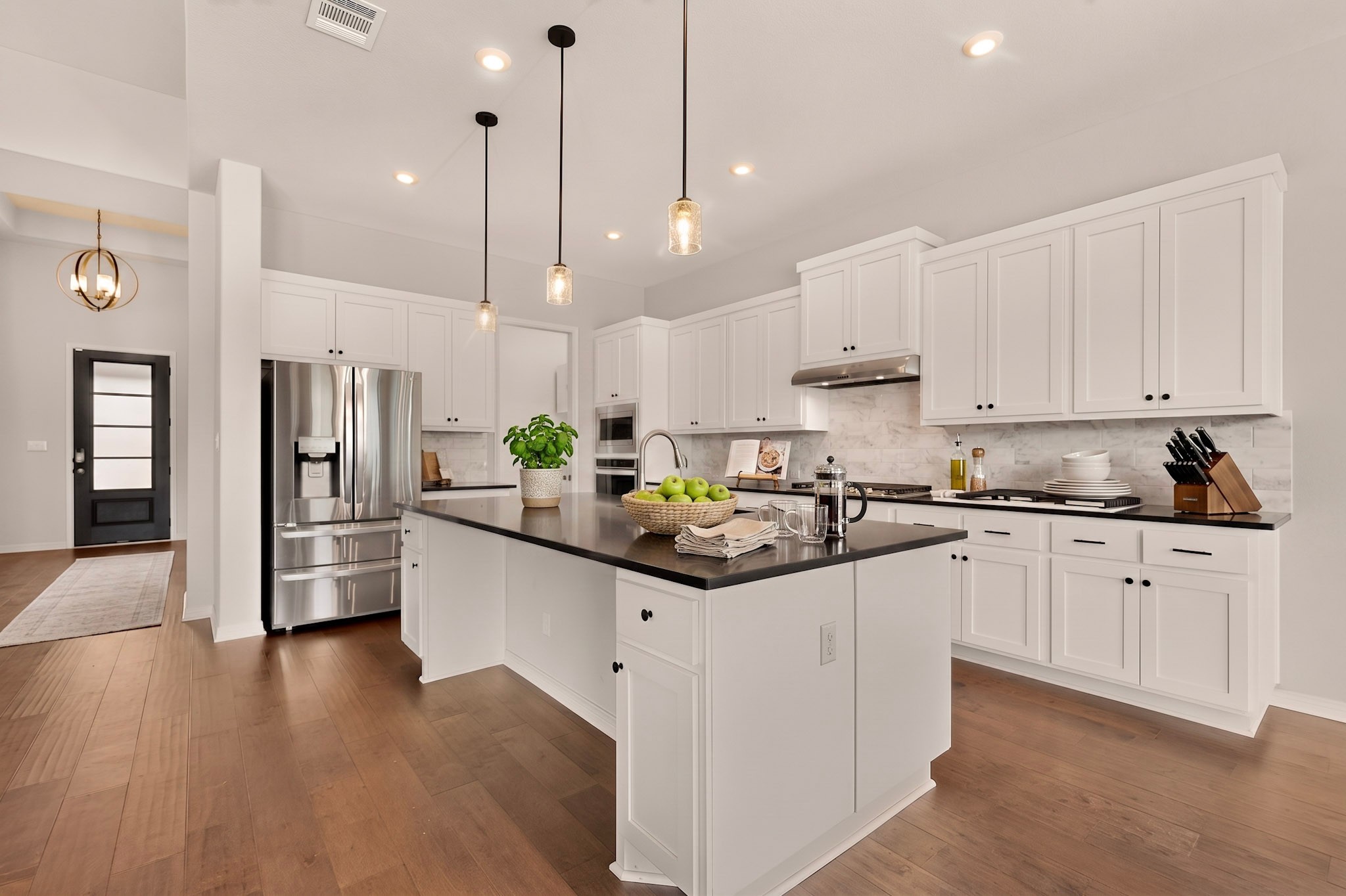 2433 La Mirada Street Leander, TX 78641 - Photo 6 of 25 Prepare culinary delights in this well-appointed kitchen, featuring a spacious island and gleaming hardwood floors.