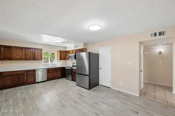 a kitchen with stainless steel appliances granite countertop a refrigerator a sink dishwasher a stove with wooden cabinets and floors