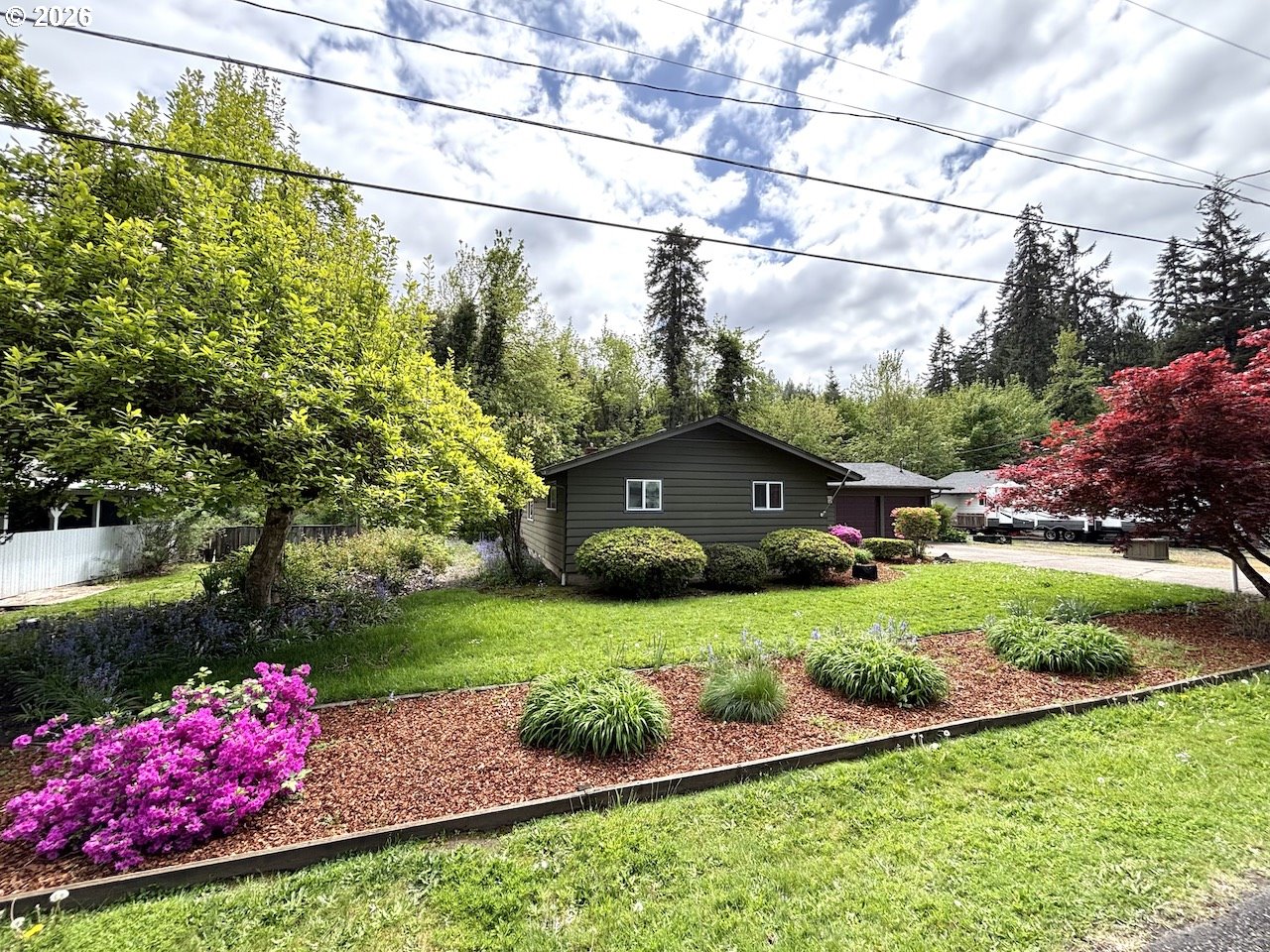 38684 Natures Garden Street Springfield, OR 97478 - Photo 2 of 26 a view of a garden with a lot of flower plants and wooden fence