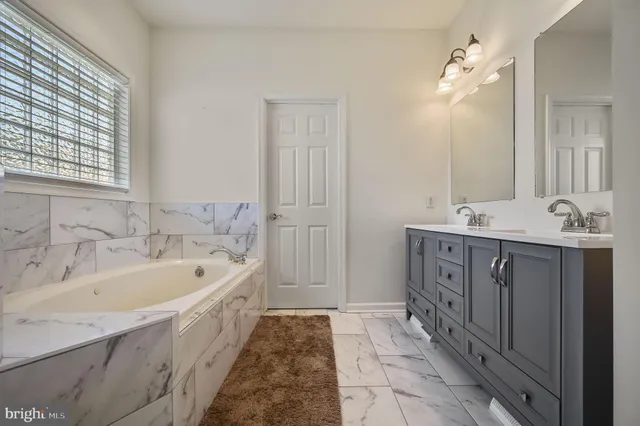 a spacious bathroom with a tub sink and mirror