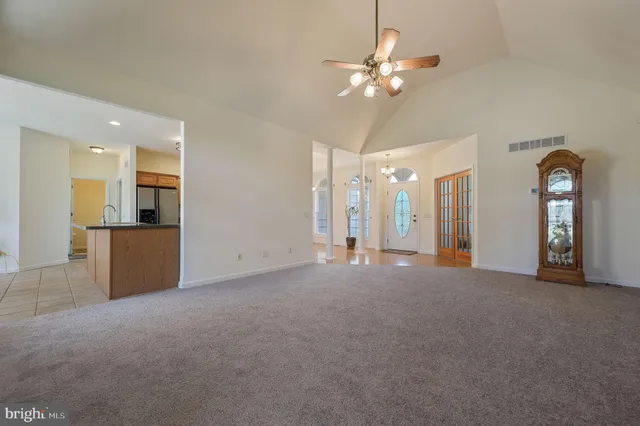 a view of a livingroom with a chandelier fan and a large kitchen space