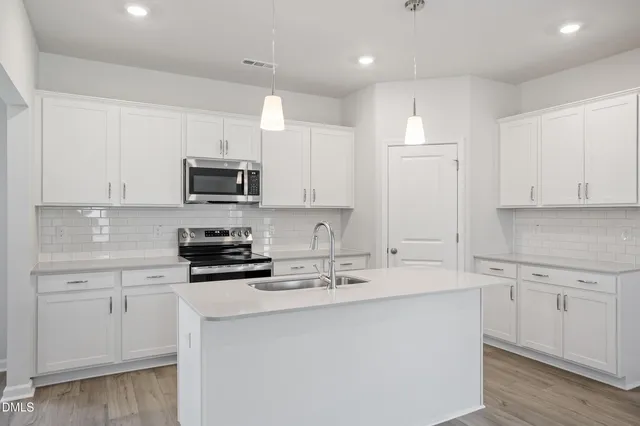 a kitchen with kitchen island white cabinets appliances and a sink