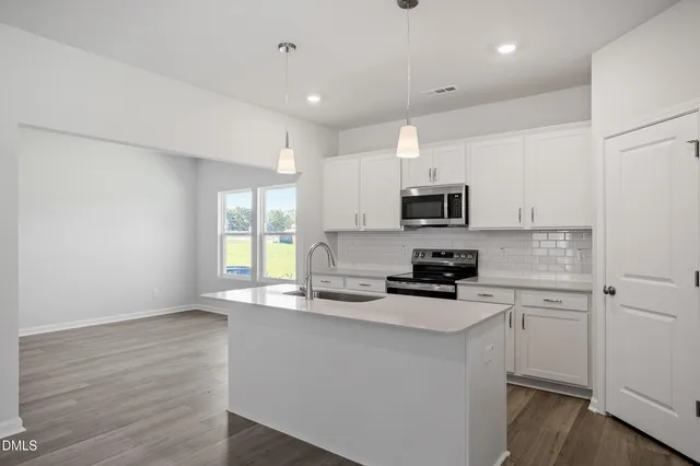 a kitchen with granite countertop white cabinets appliances a sink and a window