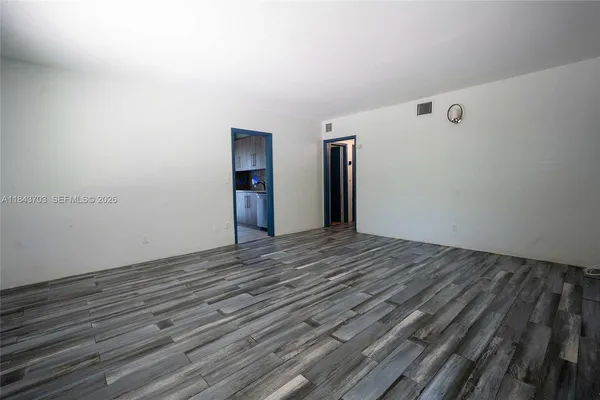 a view of an empty room with closet and a window