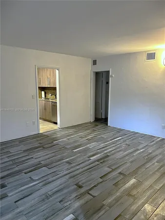 a view of an empty room with wooden floor and closet