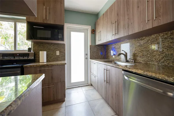 a kitchen with granite countertop a stove top oven microwave and cabinets