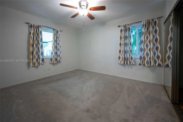 an empty room with windows and fan