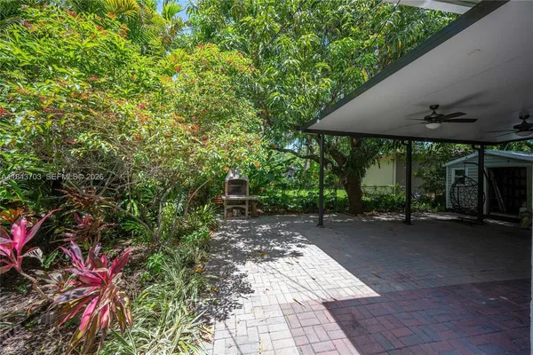 a backyard of a house with table and chairs under an umbrella