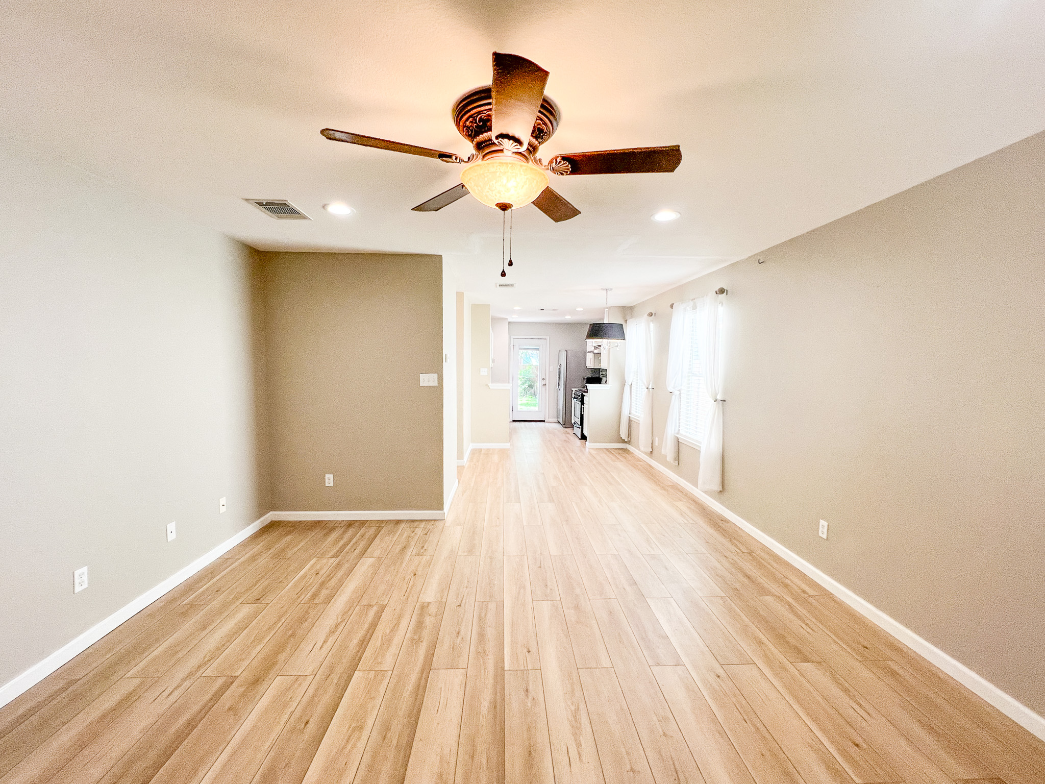 298 Jack Rabbit Lane Buda, TX 78610 - Photo 23 of 24 An open floorplan living area flows seamlessly into the kitchen, showcasing continuous wood flooring.