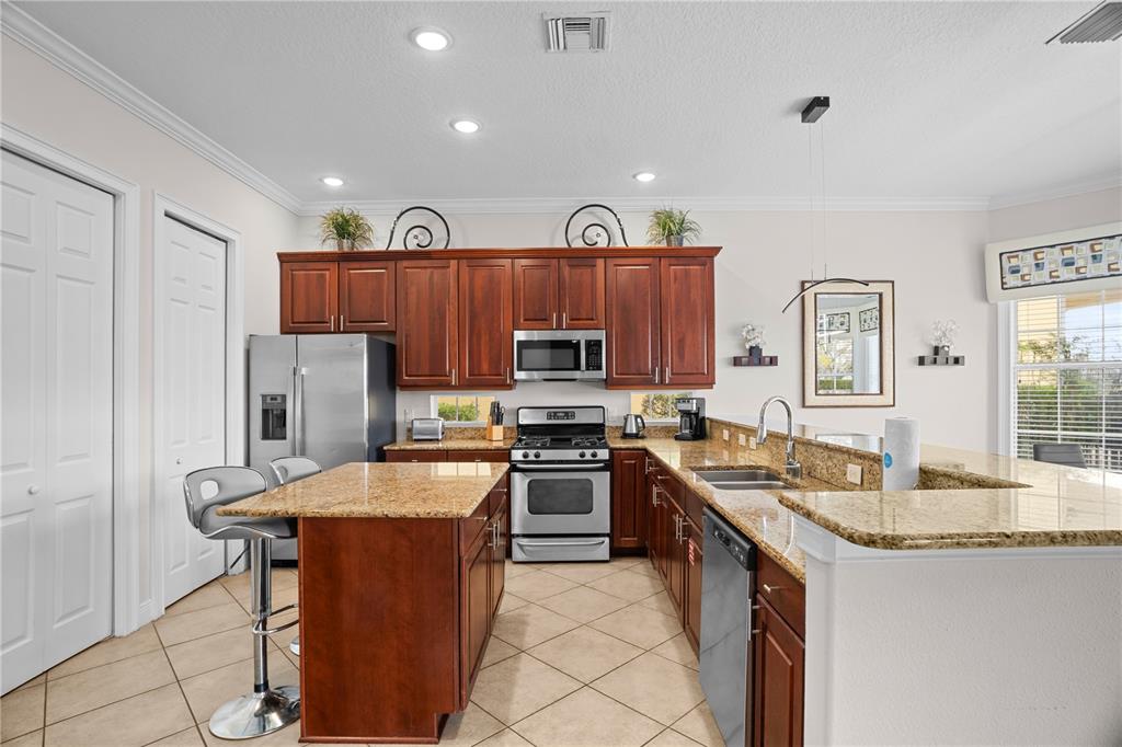 7388 Gathering Court Reunion, FL 34747 - Photo 12 of 56 a kitchen with stainless steel appliances granite countertop a stove top oven a sink and dishwasher