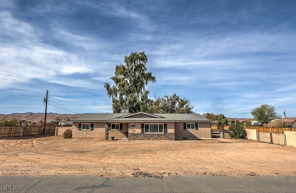 Ranch-style home featuring stone siding and a newer metal roof