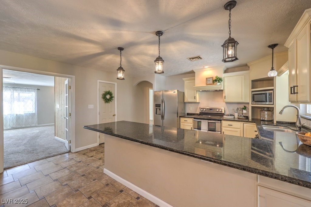3811 Skyline Street Logandale, NV 89021 - Photo 10 of 58 Kitchen with decorative light fixtures, granite countertops, stainless steel appliances, arched walkways, and eat up bar