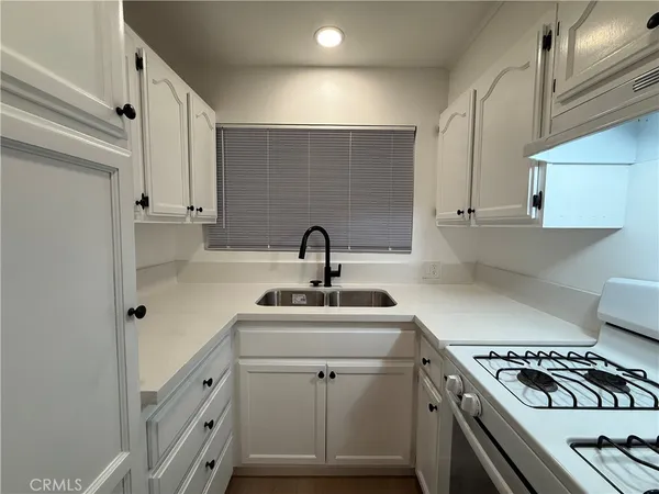 a kitchen with sink a stove and white cabinets