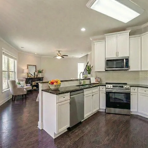 a kitchen with stainless steel appliances kitchen island granite countertop a stove and a sink