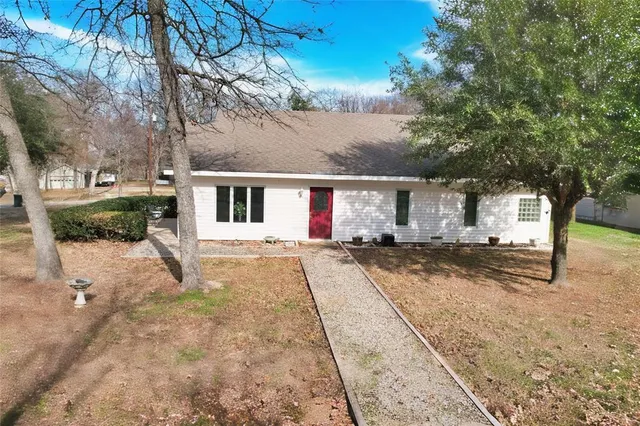 a view of a house with a yard and large tree