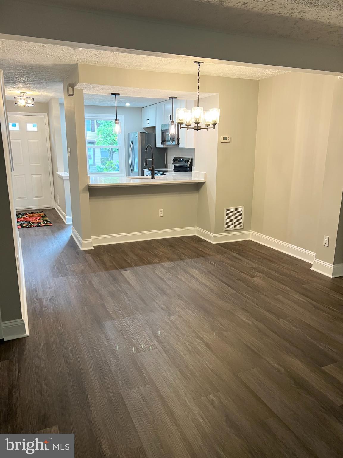 8442 Sugar Creek Lane Springfield, VA 22153 - Photo 6 of 39 an empty room with wooden floor and kitchen view