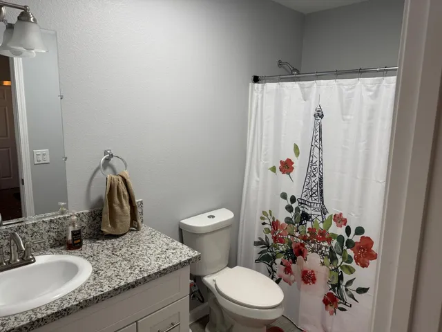 a bathroom with a granite countertop sink a toilet and a mirror