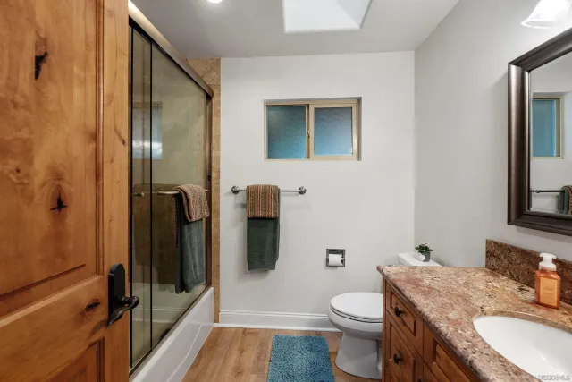a view of a livingroom with a flat screen tv wooden floor and a ceiling fan