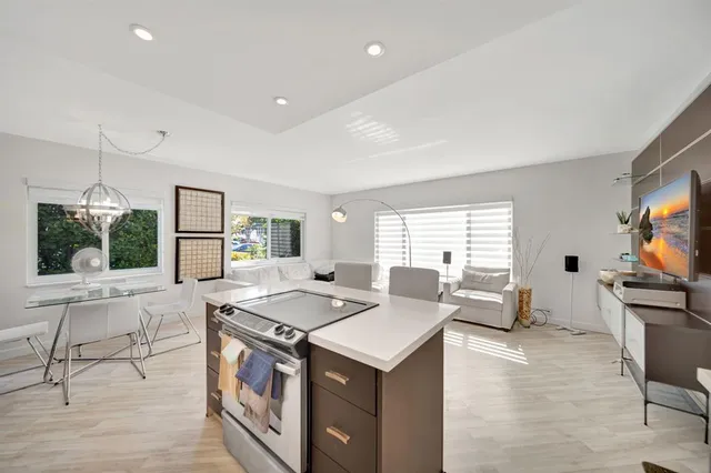 a open kitchen with stainless steel appliances granite countertop a stove top oven a sink dishwasher a dining table and chairs with wooden floor