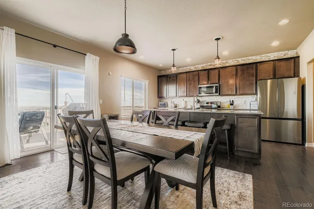 a kitchen with stainless steel appliances a dining table chairs refrigerator and microwave