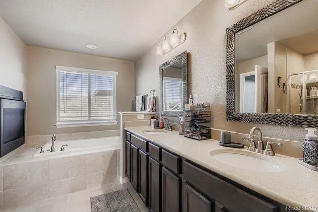 a bathroom with a granite countertop sink double vanity granite tub shower and a mirror