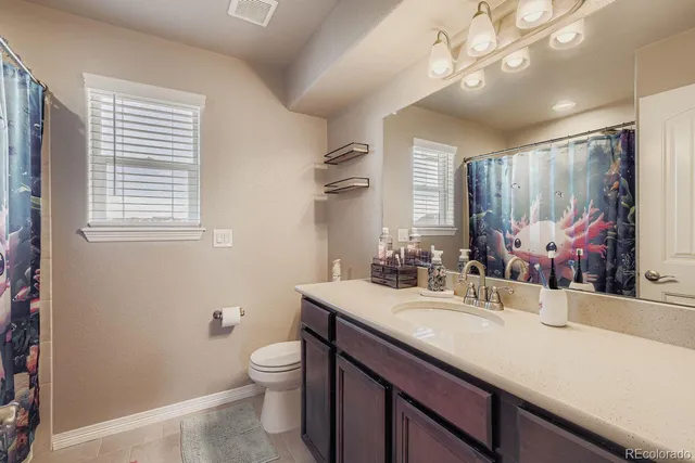 a bathroom with a granite countertop sink toilet a large mirror and a window