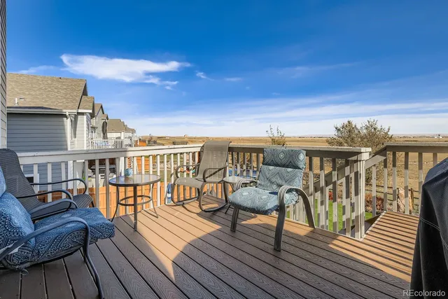 a view of a roof deck with table and chairs a barbeque with wooden floor and fence