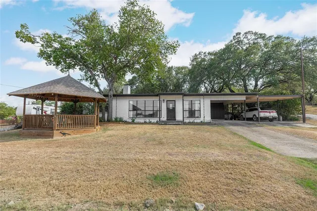 a front view of a house with a garden and trees