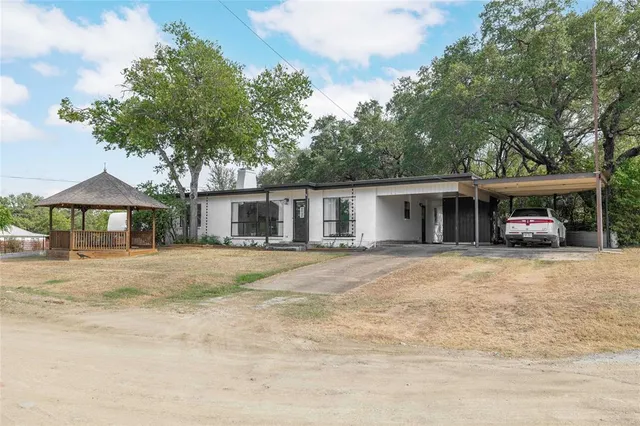 a front view of a house with a garden and trees