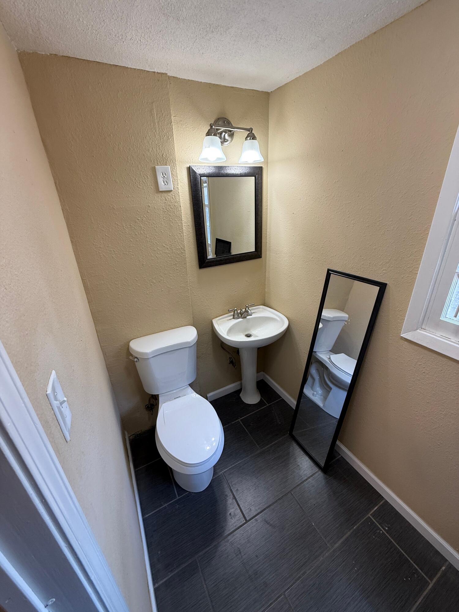 2805 27th Street Lubbock, TX 79410 - Photo 10 of 11 a bathroom with a toilet a sink and mirror