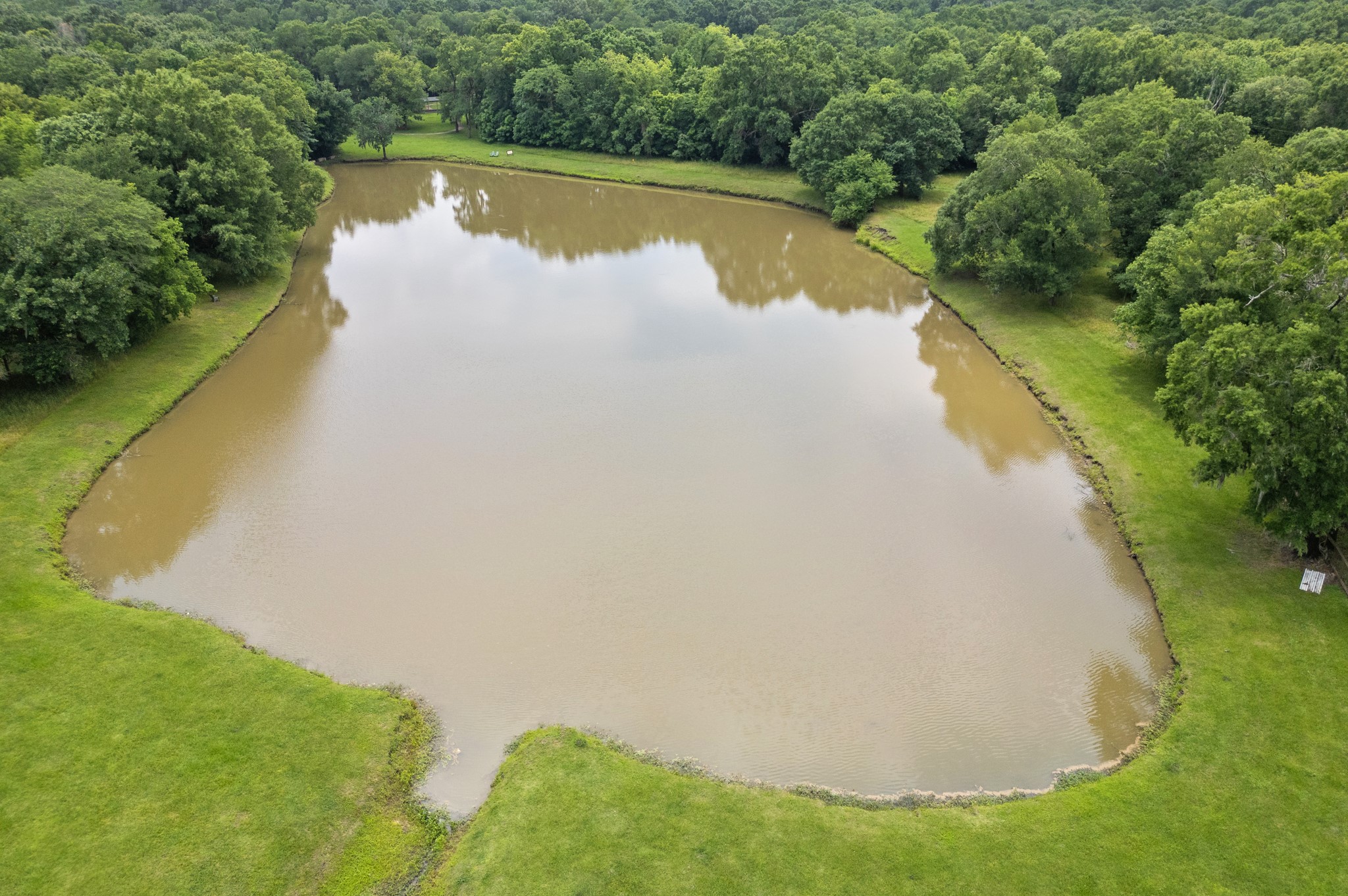 215 Center Street Cleveland, TX 77327 - Photo 31 of 38 a view of a lake with a yard and trees in the background