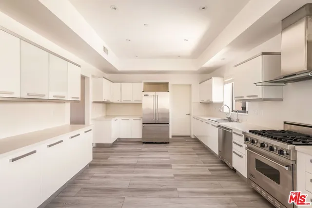 a large kitchen with cabinets wooden floor and stainless steel appliances