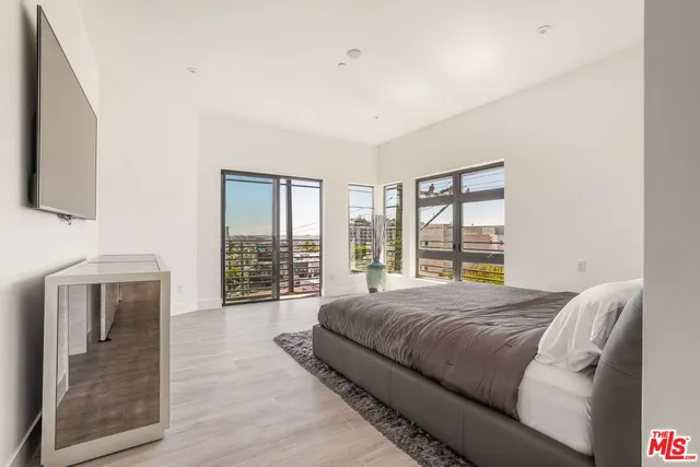 a spacious bedroom with a large bed and a flat tv screen on dresser