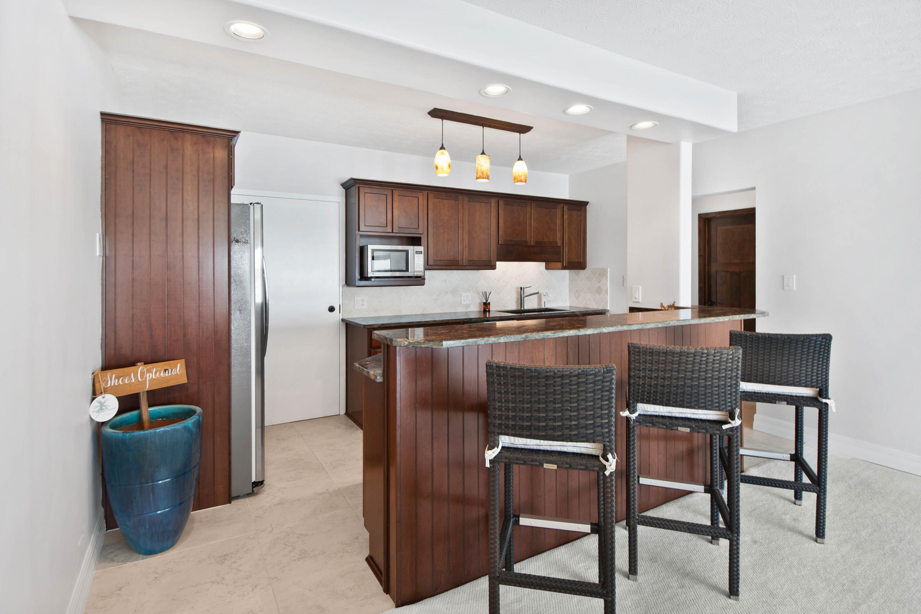 60 West Pelican Street, Unit 206 Naples, FL 34113 - Photo 17 of 29 a kitchen with kitchen island a dining table chairs and a refrigerator