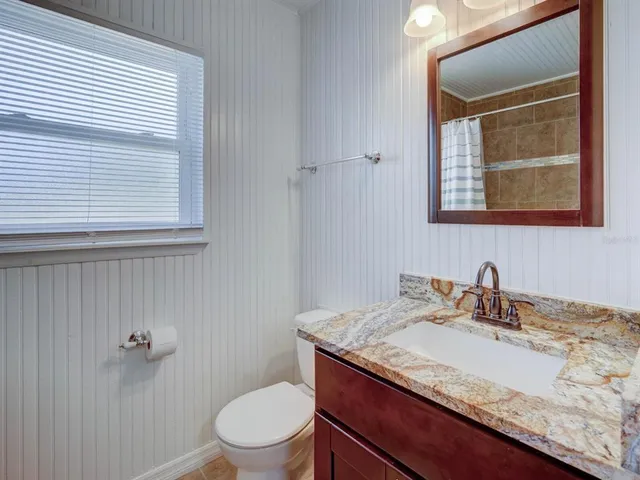 a bathroom with a granite countertop sink toilet and mirror