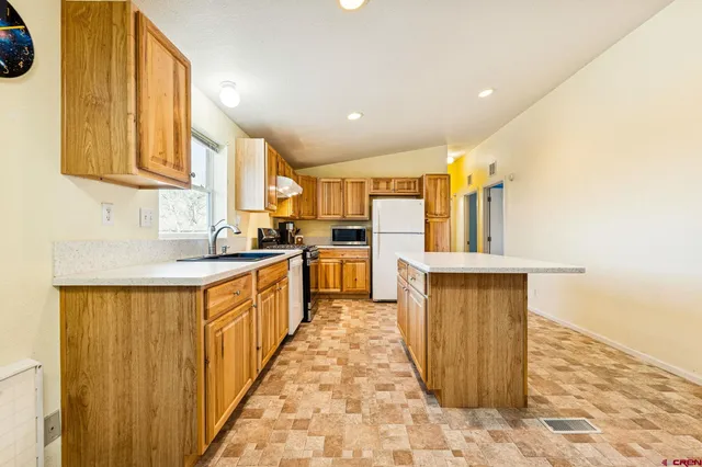 a kitchen with stainless steel appliances granite countertop a sink a stove a refrigerator a microwave oven with white cabinets and wooden floor