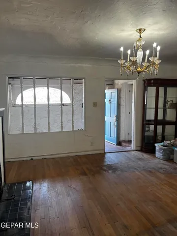 an empty room with wooden floor chandelier and windows
