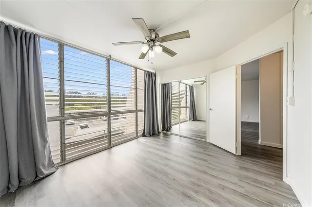 an empty room with wooden floor fan and windows