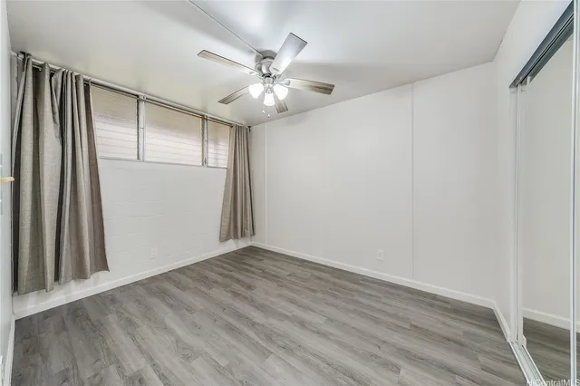 an empty room with wooden floor and fan