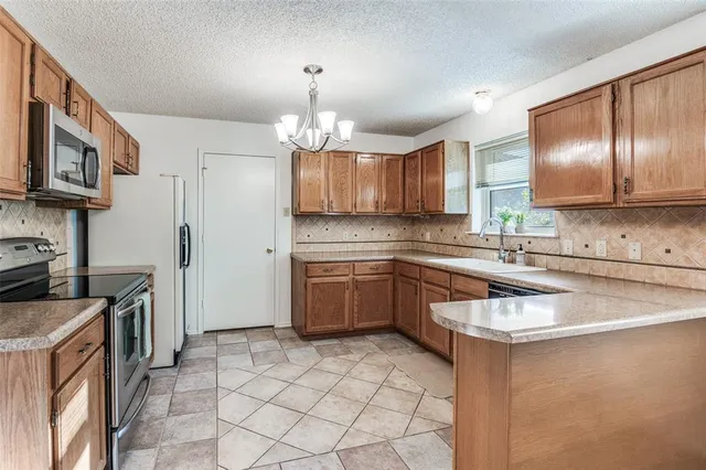 a kitchen with stainless steel appliances granite countertop a sink a stove a refrigerator cabinets and chairs