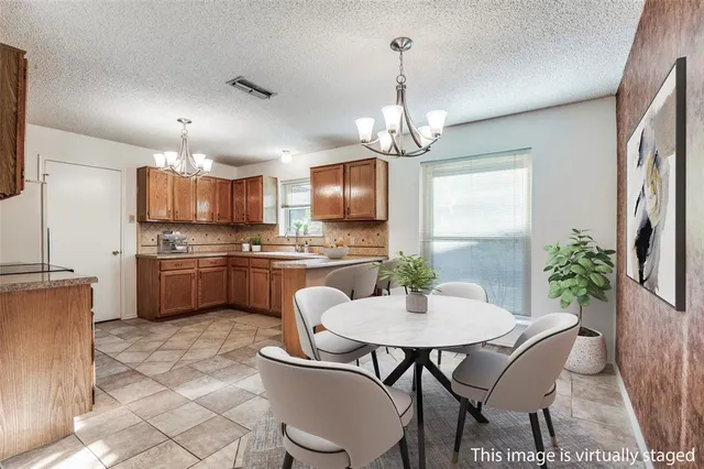 a kitchen with kitchen island a chandelier dining table and appliances