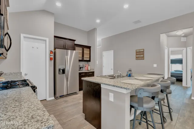 a kitchen with stainless steel appliances granite countertop a table chairs and a refrigerator