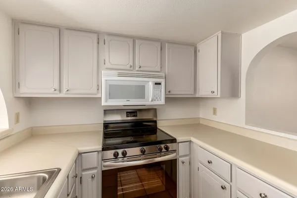 a kitchen with white cabinets and appliances