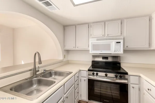 a kitchen with white cabinets sink and appliances