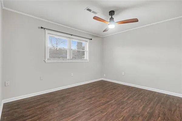 an empty room with wooden floor and ceiling fan