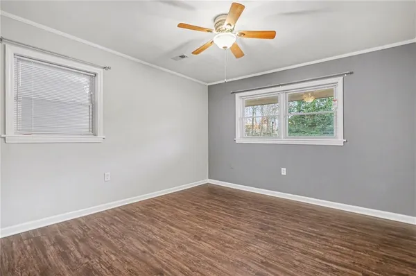 a view of an empty room with window and wooden floor