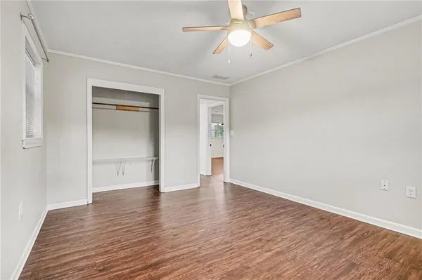 an empty room with wooden floor and ceiling fan
